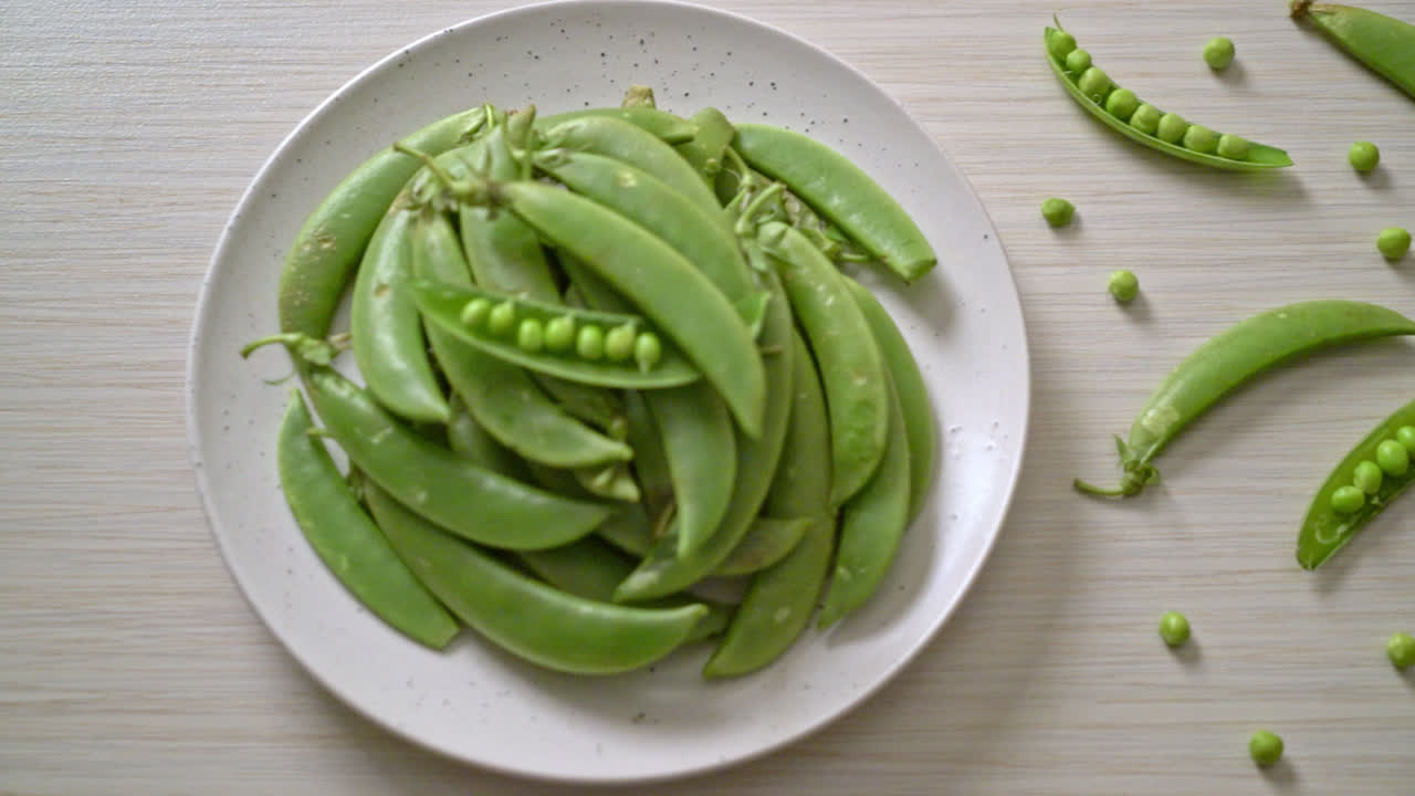 하얀 접시에 신선한 달콤한 녹색 완두콩