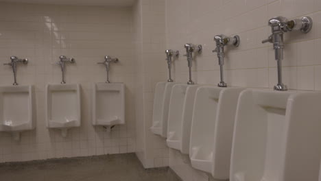 urinals in public rest room washroom on white tile walls - empty bathroom