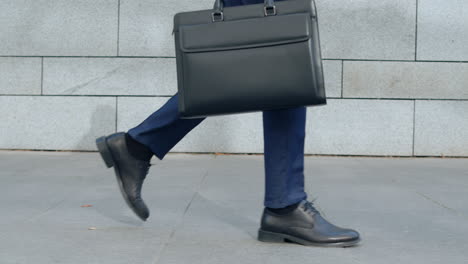 businessman legs walking on city street. worker with briefcase going for work