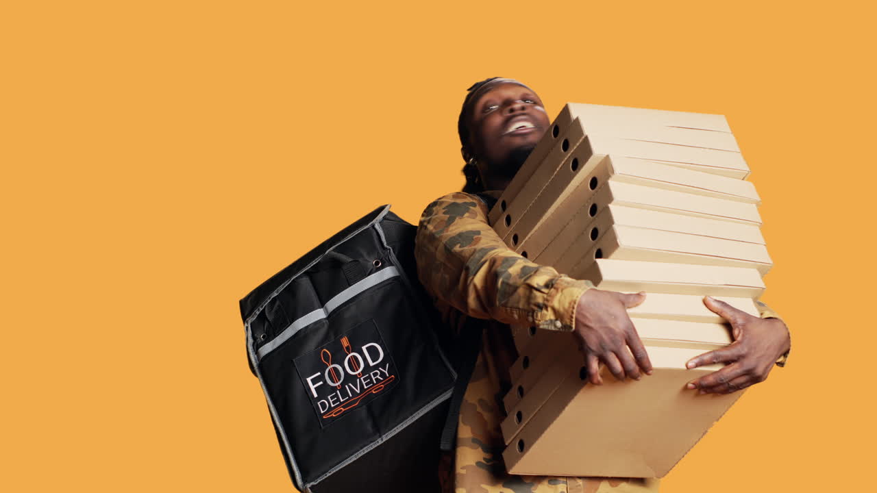 Young deliveryman giving huge stack of pizza boxes to client,
