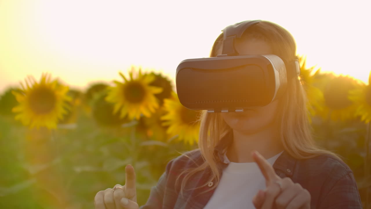 la mujer está trabajando en gafas vr. está involucrada en el proceso de trabajo. es un día soleado perfecto en el campo de girasoles.