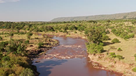 Luftdrohnenaufnahme-Der-Masai-Mara-Flusslandschaft,-Die-Sich-In-Einer-Wunderschönen-Landschaft-Im-Masai-Mara-Nationalreservat-In-Kenia,-Afrika,-Windet,-Weite-Aufnahme-Mit-Viel-Grün-Und-üppigen-Grünen-Bäumen