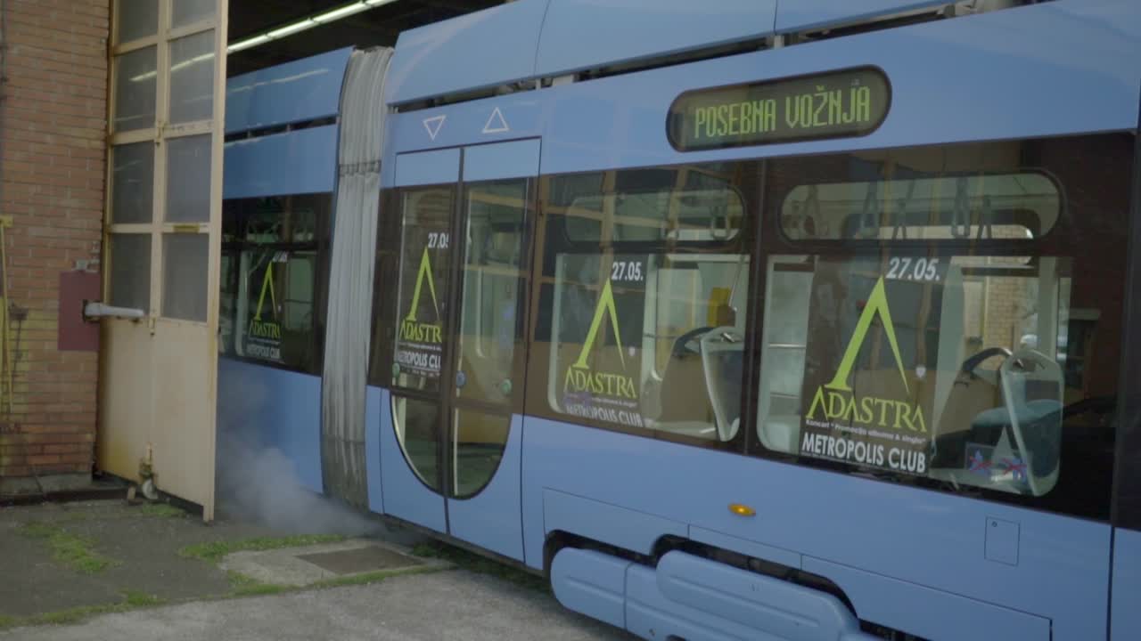 A bright blue tram exits the main garage in downtown Zagreb after being serviced, Croatia