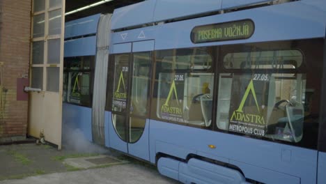 a bright blue tram exits the main garage in downtown zagreb after being serviced, croatia