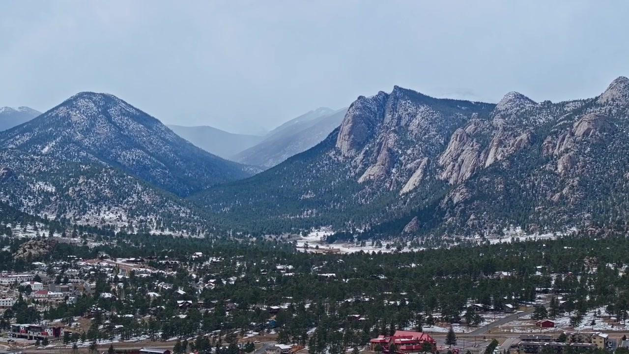 Valle di Estes Park con area residenziale e sfondo di catena montuosa innevata, panoramica aerea con drone.