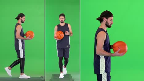 attractive cheerful young fit basketball player walking with a ball in his hands on a green screen, chroma key