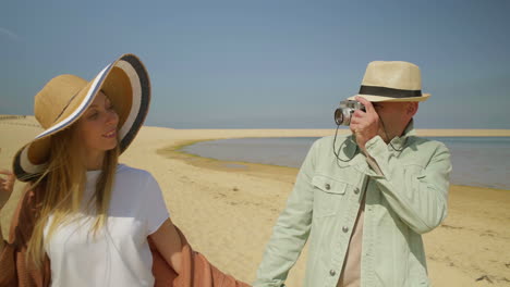 hombre fotografiando a su novia en una playa de arena