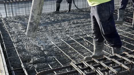 workers apply a layer of cement to create the floor and roof of a large area under construction