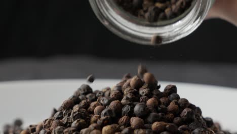 los granos enteros de pimienta negra secos se vierte en el plato