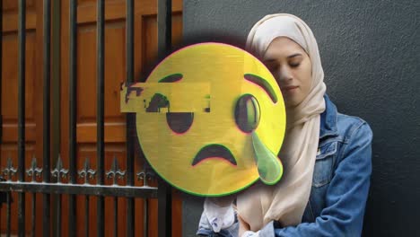 Animation-of-emoji-crying-over-muslim-woman-using-smartphone