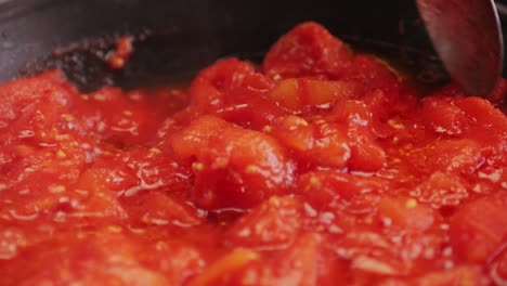 cooking fresh peeled canned tomato juice sauce with mozzarella cheese in pan, peeled tomatoes boiling in their own juice, making tomatoes pasta sauce .top view close up, italian traditional cuisine food.
