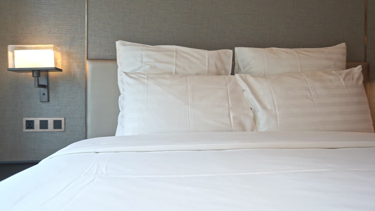 гостиничная кровать с белым постельным бельем и подушками в современной спальне