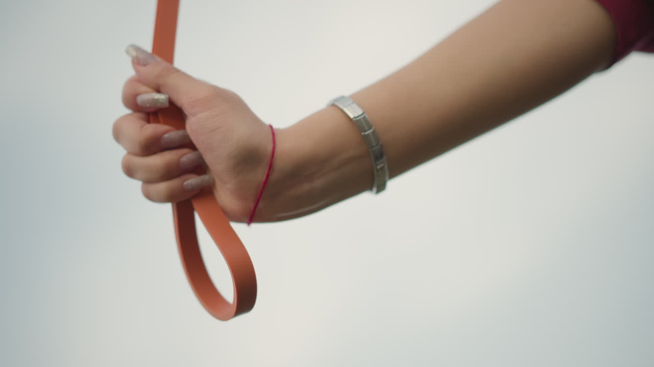 Hand Grasping Leash With Stylish Accessory, Closeup Of Hand With Bracelet And Leash Against Sky Background, Precise Image Capturing Hand Adorned With Bracelet Holding Leash Under Soft Outdoor Sky