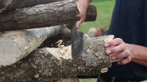 young man chops wood for campfire with machete