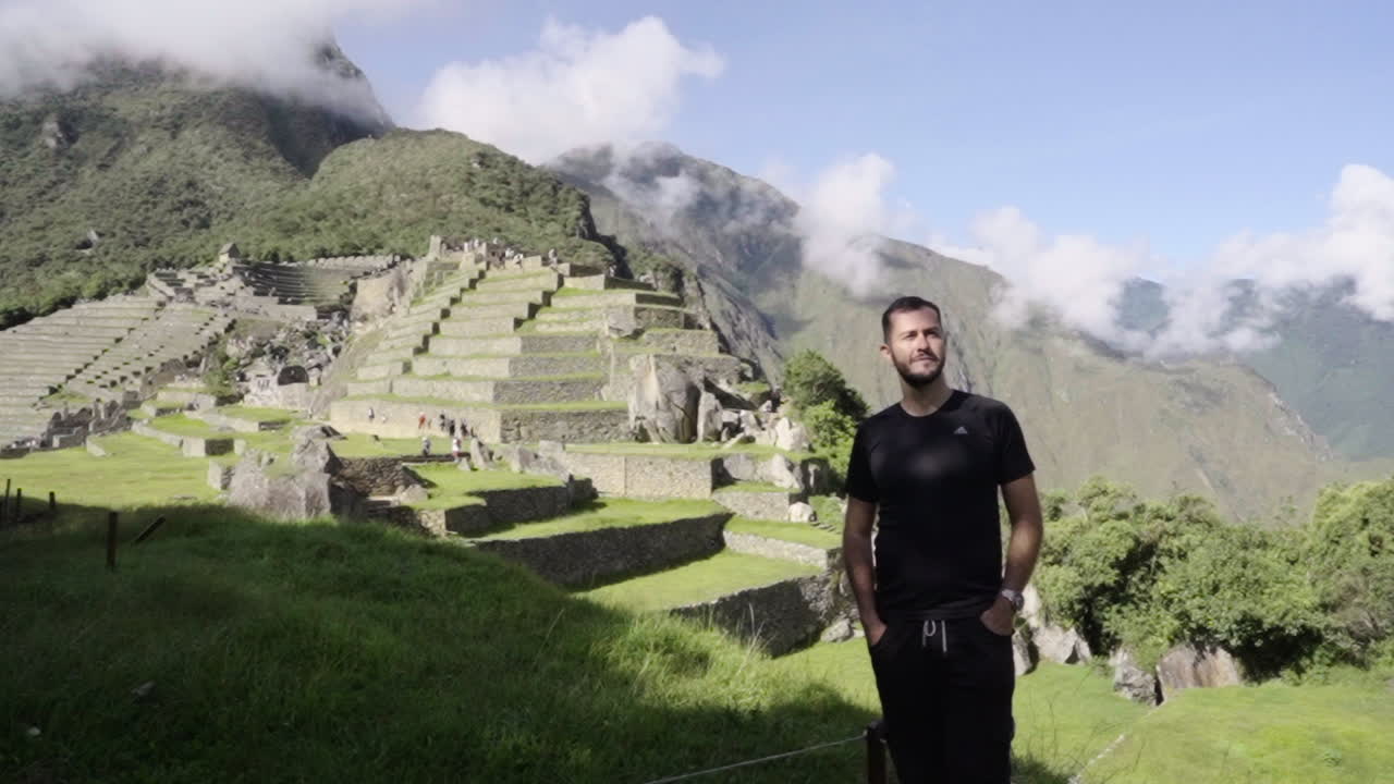 Tourist man contemplates Machu Picchu. Traveler with lost city landscape in background. Wanderer adventure
