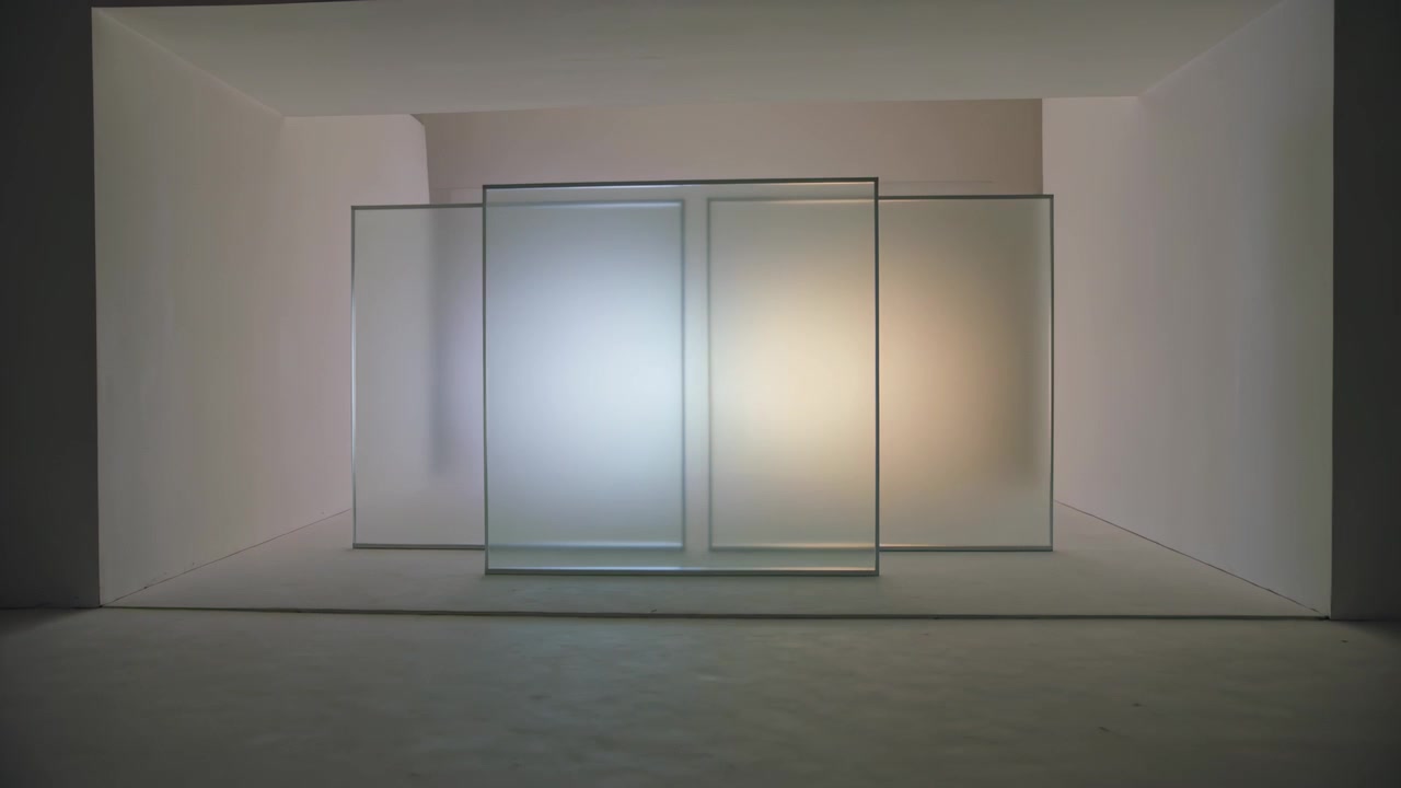 Pannello frontale scorrevole su binario che si sposta da destra a sinistra tra vetri satinati in una nicchia, mescolando luce fredda o calda.