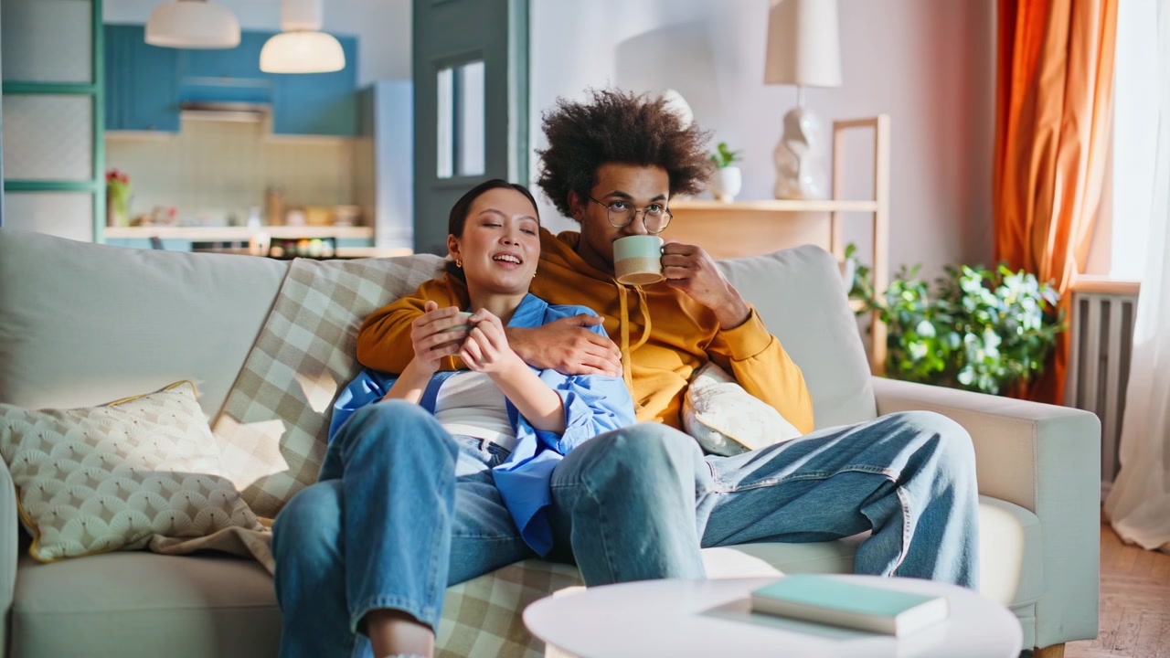 Ungt par drikker kaffe i sofaen derhjemme. Hyggelig weekendmorgen sammen