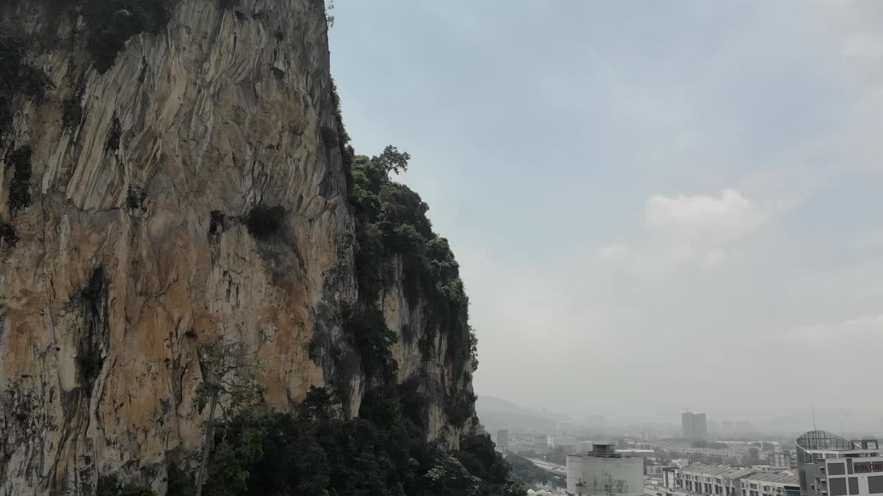 Drone shot of a mountain- cliff edge in Batu, just by the Batu caves. Panning shot of the city and the huge cliff edge.