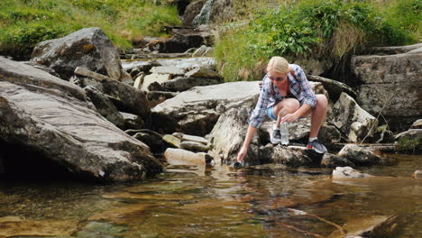 a woman drinks clean water recruited from a stream norway waterfall tvindefossen 4k video