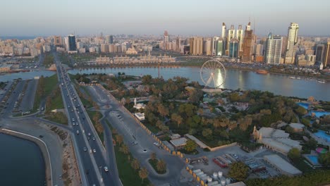 drone view of sharjah's khalid lake and city skyline on a beautiful evening, eye of emirates wheel, travel tourism business in the united arab emirates