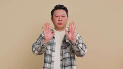 annoyed irritated asian man covering ears gesturing no avoiding advice ignoring noise loud voices