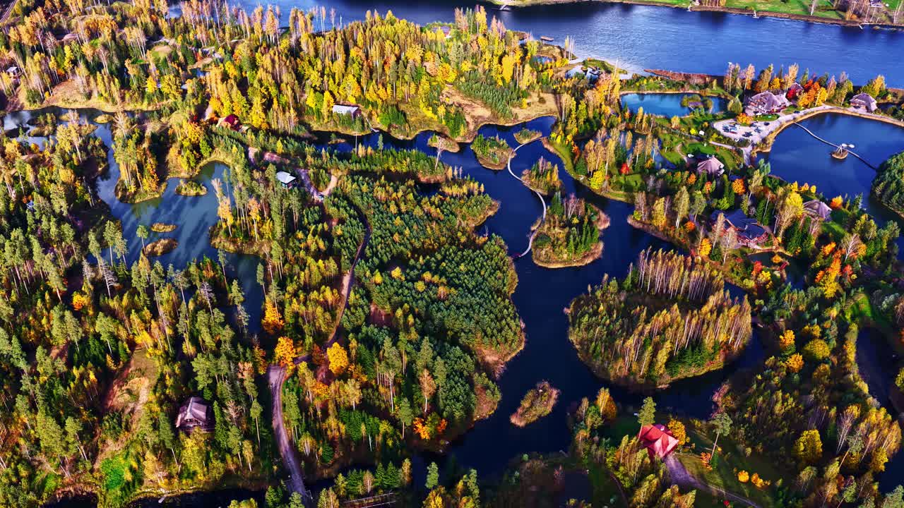 Aerial view of autumn forest by a lake with winding paths and cozy ...