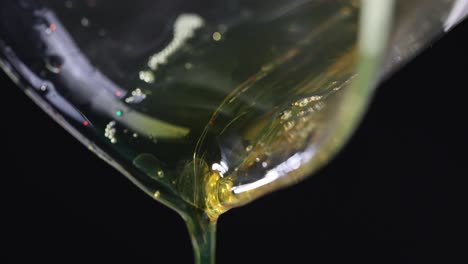 close-up of viscous golden liquid pouring with glitter on black background