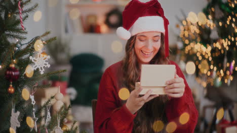 Erstaunte-Frau-Mit-Weihnachtsmütze-öffnet-Hölzerne-Geschenkbox-Im-Dekorierten-Zuhause