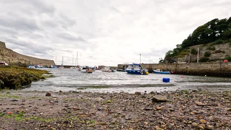 waves hitting shore with boats in background