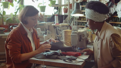 multiethnic female colleagues making leather shoes in workshop