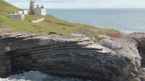 historic lighthouse on coastal cliffs, drone descent with tilt