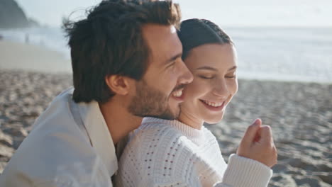 smiling woman feeding husband sitting beach sand sunny evening close up.