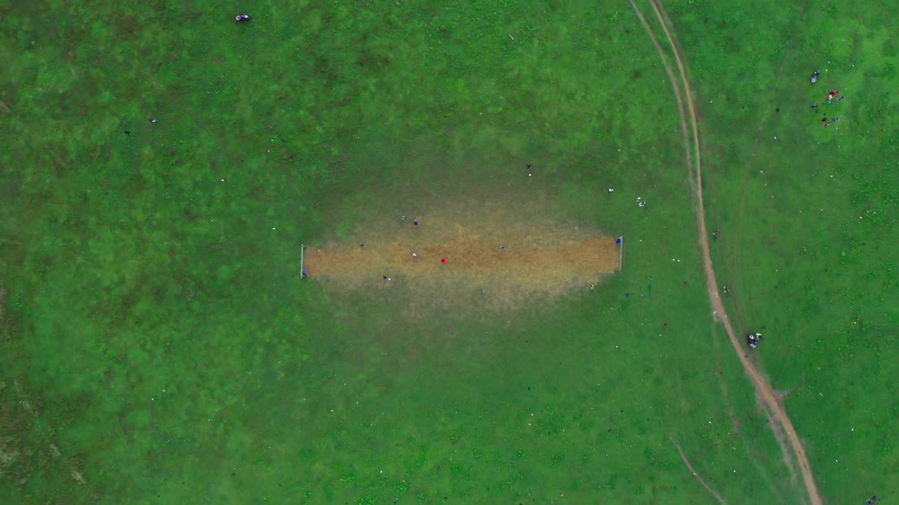 4k aerial bird's eye drone shot kids playing football on green field