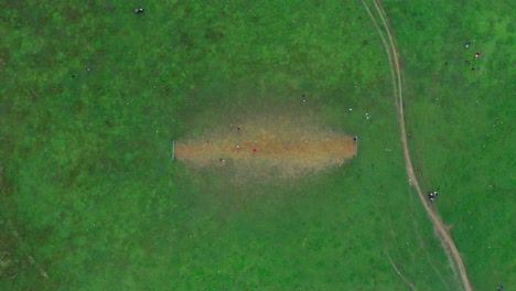 4k aerial bird's eye drone shot kids playing football on green field