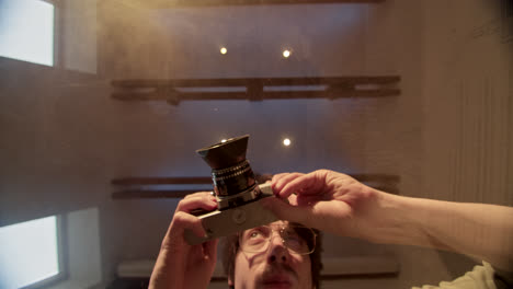 person holding and adjusting a vintage camera, viewed from a low angle