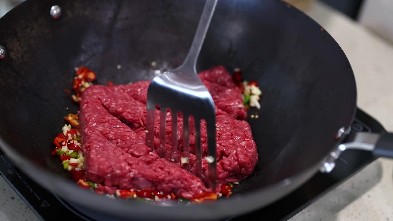 Beef is stir-fried with chilli and garlic in a wok, creating a vibrant and aromatic dish