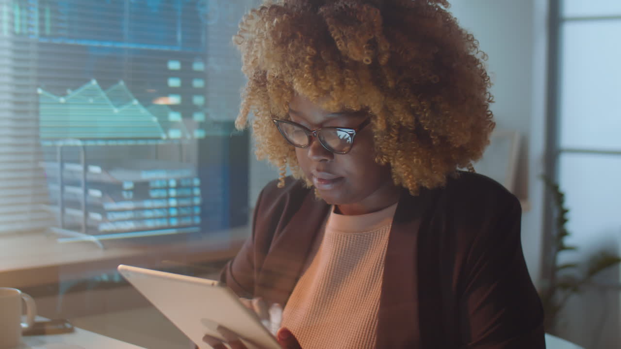 African American Businesswoman Using Tablet in Office at Night