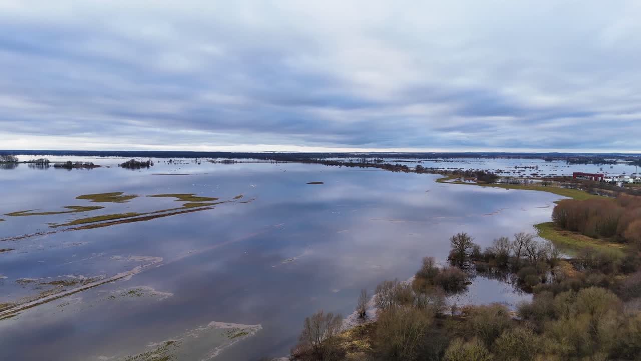 establecimiento aéreo de llanuras de hierba inundadas y árboles sin hojas, el agua refleja el cielo nublado