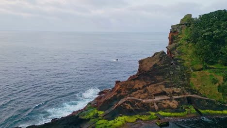 summer rocky coastline formation on cloudy day. flight over endless sea water