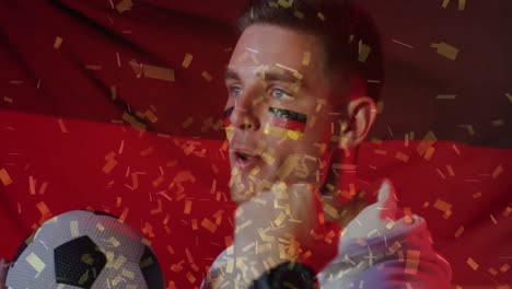 Animation-of-confetti-falling-over-caucasian-footballer-celebrating-with-german-flag