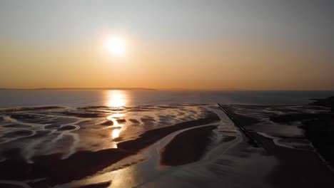 Vibrant-sky-gradient-at-sunset-reflecting-onto-beach-tidal-pools,-Wales