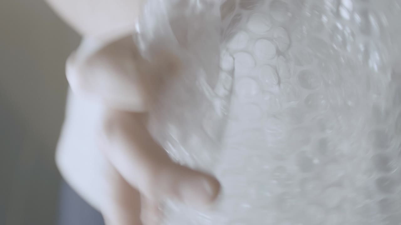 Detail of a piece of bubble wrap held by two hands, packing paper for fragile things for moving house