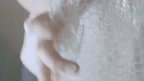 Detail-of-a-piece-of-bubble-wrap-held-by-two-hands,-packing-paper-for-fragile-things-for-moving-house