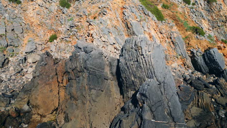 rugged dark rock formation sunny day aerial view. wild rough volcanic cliffs.