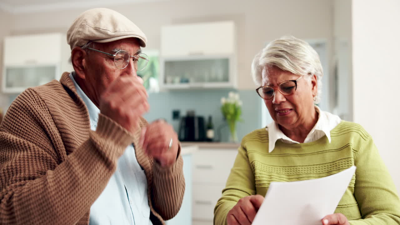 Worried elderly couple reviewing documents at home