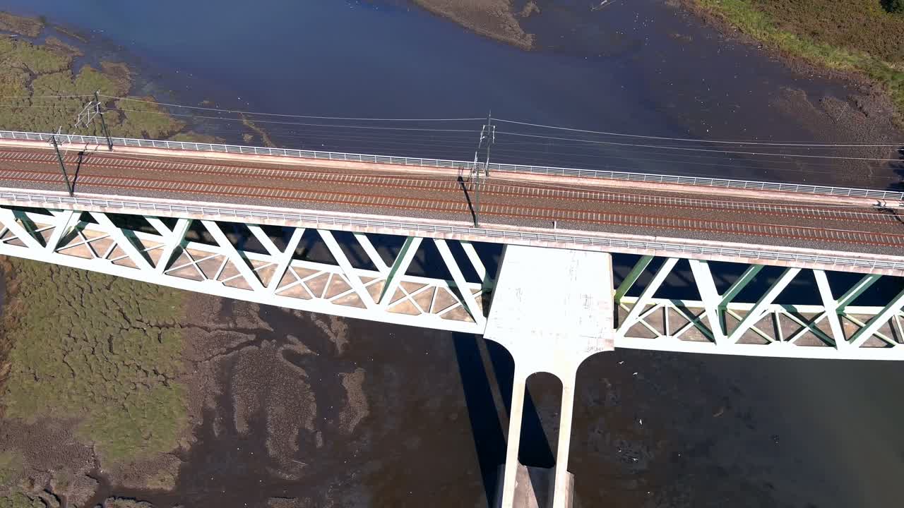 volando sobre el puente ferroviario con líneas eléctricas sobre el río ulla con bajo nivel de agua, gaviotas volando bajo, disparos de drones cenitales viajando hacia adelante, catoira, galicia, españa