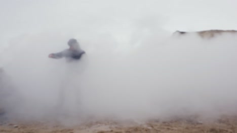 Adult-tourist-walk-through-vapor-cloud-on-slippery-Icelandic-gravel-ground