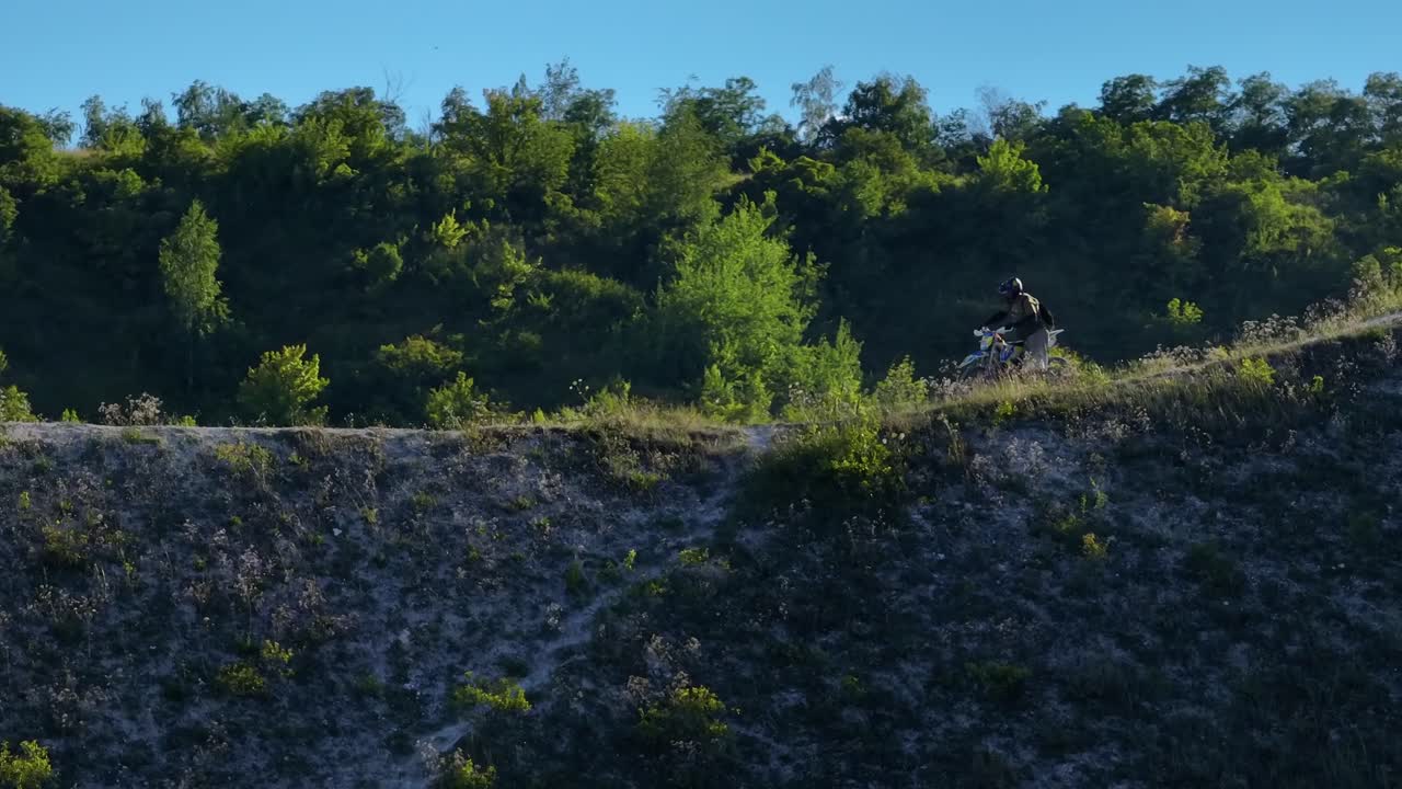 piloto de motocross en un sendero en la ladera de una colina