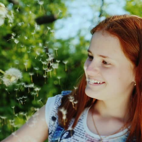 a girl with bright red hair has fun playing with dandelion flowers 2