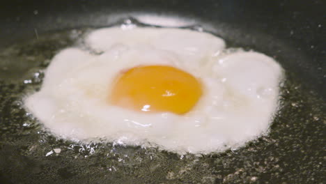 splashing fried egg with hot oil to cook the top. cooking protein rich breakfast healthy food